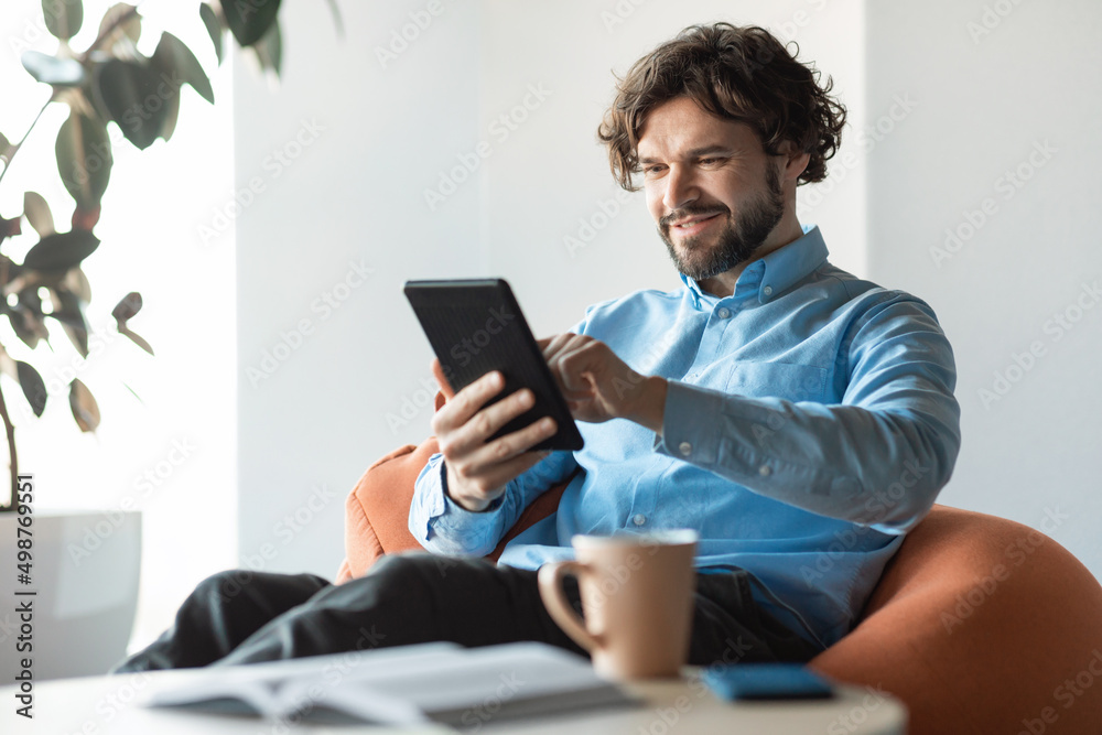 Poster portrait of smiling mature man using digital tablet at office