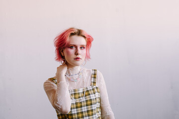 Young fashion stylish woman standing vintage studio, bright make up and colored hair, looking at...