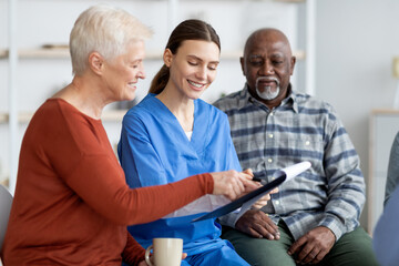 Cheerful young woman doctor having conversation with senior patients