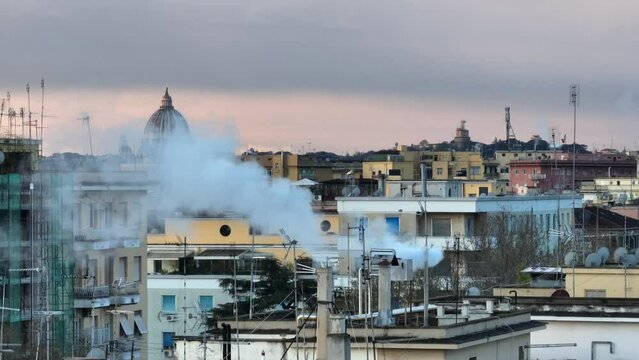 I tetti di Roma, i comignoli che fumano sullo sfondo la cupola di San Pietro
Riscaldamento, consumo del gas e inquinamento in citt&agrave;.
