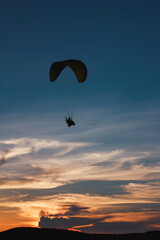 Fototapeta na wymiar silhouette paramotor or paraglider fly over the sea with beautiful sunset sky background.