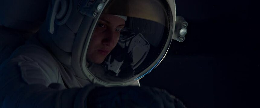 Female astronaut performing spacewalk, working on a outer part of a space craft. Shot with 2x anamorphic lens