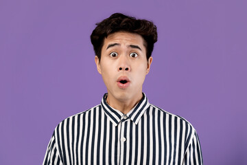 Surprised Asian man staring at camera at studio