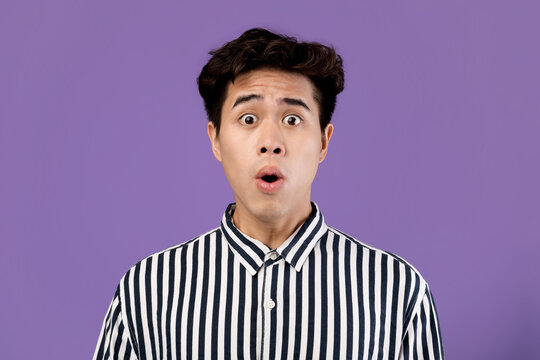 Surprised Asian man staring at camera at studio