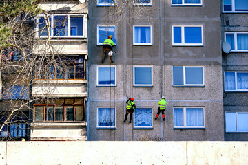 Window cleaning urban alpinism brigade on building with windows and balconies on spring cleaning day