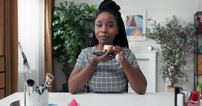 A popular makeup blogger records vlog, video for social media, influencer collaborates with cosmetics brand, girl reviews a rice powder she applies to face, she likes the smell of the product.