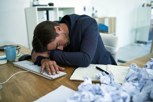 Drowning In Paperwork. Shot Of A Stressed Out Businessman Passed Out At His Desk Overwhelmed By Paperwork.