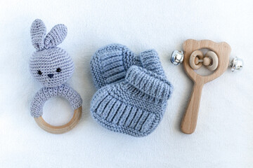 Knitted shoes for newborns, handmade knitted amigurumi rabbit and wooden baby toy on white...