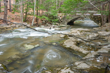 Eddy in cascade going under granite arched bridge