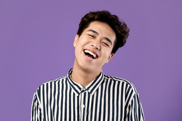 Fototapeta premium Portrait of smiling Asian guy posing laughing at studio