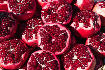 a lot of ripe red pomegranates with a cut off top, close-up background