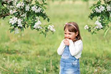 Fototapeta premium Portrait of a girl in a spring garden near blooming apple trees