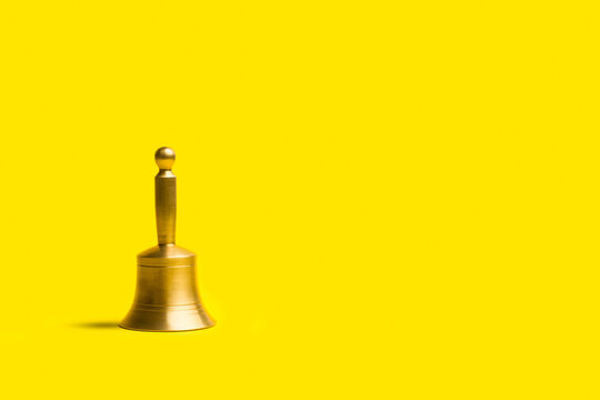 Campana de bronce con mango sobre un fondo amarillo aislado y aislado. Vista de frente y de cerca. Copy space