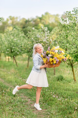 young blonde woman with a large basket of flowers in the spring garden