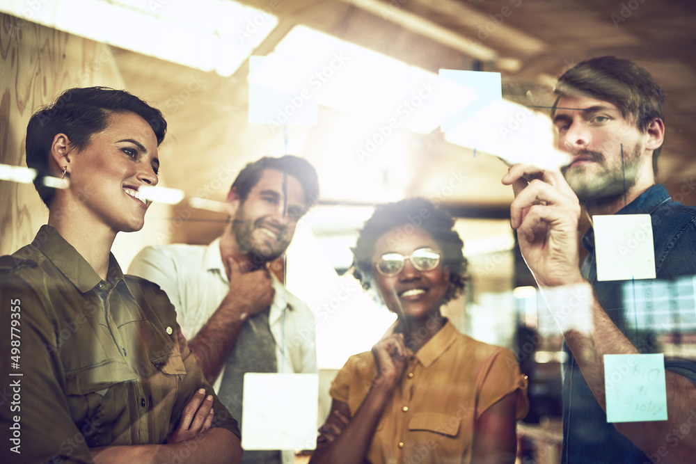 Poster setting out their strategy. shot of a group of businesspeople brainstorming with notes on a glass wa