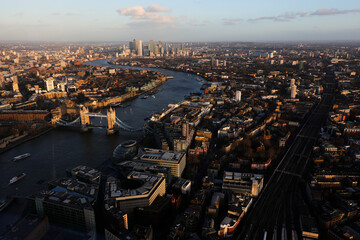 London view with the most iconic symbol of London, Tower Bridge illuminated by the last rays of the sun before sunset and  skyline buildings in Canary Warf, view from The Shard observation deck tower.