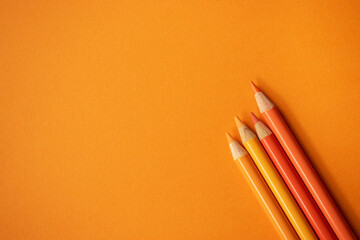 Orange Buntstifte auf orangem Hintergrund. Freiraum für Text