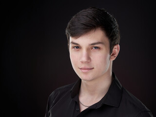 A portrait of a teenager in a black shirt on a dark red background