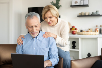 Mature family couple watching video on laptop - obrazy, fototapety, plakaty