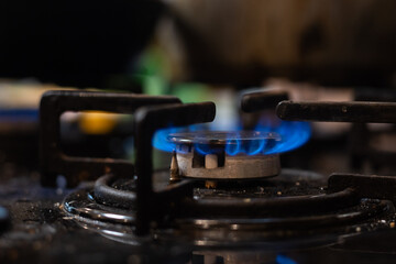 Fototapeta na wymiar Closeup shot of blue fire from domestic kitchen stove top. Gas cooker with burning flames of propane gas. Industrial resources and economy concept