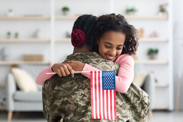 Happy girl with flag of the US hugging her mom