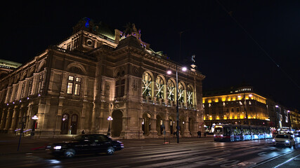 Fototapeta na wymiar Front view of the main entrance of famous Vienna State Opera house, Austria, in the historic downtown with illuminated stone facade. Blurred motion.