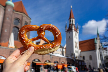 Naklejka premium holding bayern style pretzel on the victuals market with altes rathaus background in munich