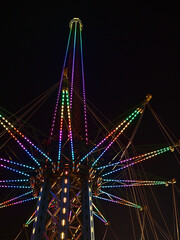 Low angle view of drop tower with colorful, illuminated structure at night in amusement park...