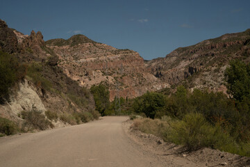 Travel. View of the dirt road across the arid desert and colorful rock formations.	
