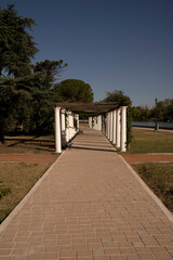 General San Martín park in a sunny day. View of the walkway, plants and decorative white columns.