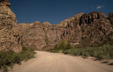 Travel. View of the dirt road across the arid desert and colorful rock formations.	
