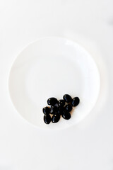 Pickled black olives on a white plate with a fork