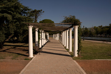 Garden design. General San Martín park in a sunny day. View of the walkway, plants and decorative white columns.