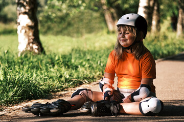 Happy child resting after playing sports on a sunny day. A girl dressed in a sports uniform and...