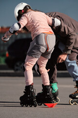 The coach teaches a young girl to roller skate. Individual lessons with a trainer.