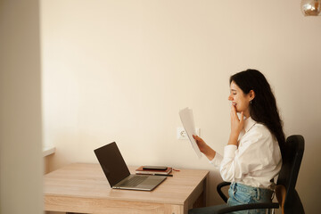 Student girl passed exam and rejoices at high mark. Online education and distance learning. Woman applicant with laptop holds papers with exam results in his hands and rejoices.