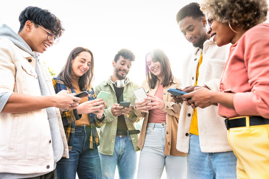 Multiracial group of smiling friends using their phones on a summer day in trip - Group of adult hipster friends using smartphone with hands - Technology, social, concept of bloggers posting content.