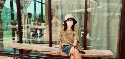 An Asian woman is sitting at a coffee shop in a sunny day.