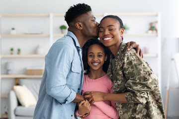 Happy african american family celebrating reunion with mom soldier