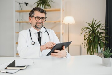 Senior doctor using his tablet computer at work