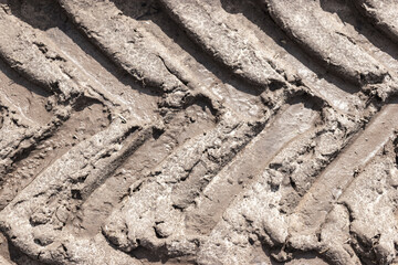 Footprint of wheel tread on the ground road. The trail from the tread of trucks wheels. Car tire tread imprint on sand, background, texture. Footprints rubber tyres from automobile. Close-up.