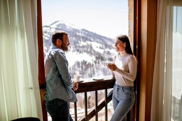Young couple with cups of hot tea at winter window