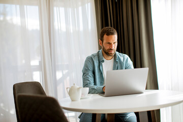 Young man using laptop and drink tea in the living room