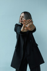 Young caucasian woman with short haircut shows stop gesture in the office. Female in black suit. The concept of a normalized work schedule