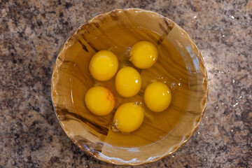 closeup of a bowl with cracked chicken eggs in a kitchen worktop