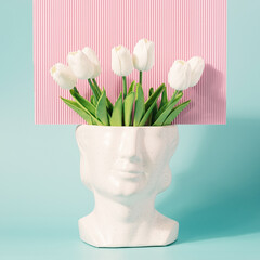 Retro head sculpture with tulip flowers on a pastel blue pink background. Spring, summer retro wave concept.
