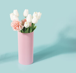 Pastel pink vase with various spring flowers on a mint background. Springtime, summer minimal concept.