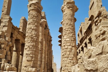 Stone pillars at the Karnak Temple in Luxor, Egypt, against blue sky.
