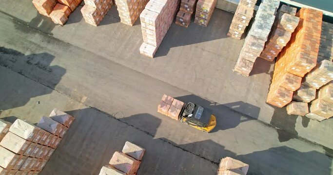 An aerial view of a forklift carrying cargo on a pallet. Warehouse outdoors.