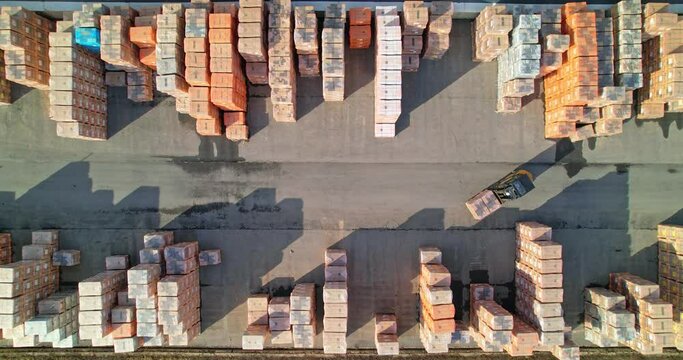 Aerial view of a forklift during operation. A forklift is carrying a pallet of goods. Warehouse outdoors.